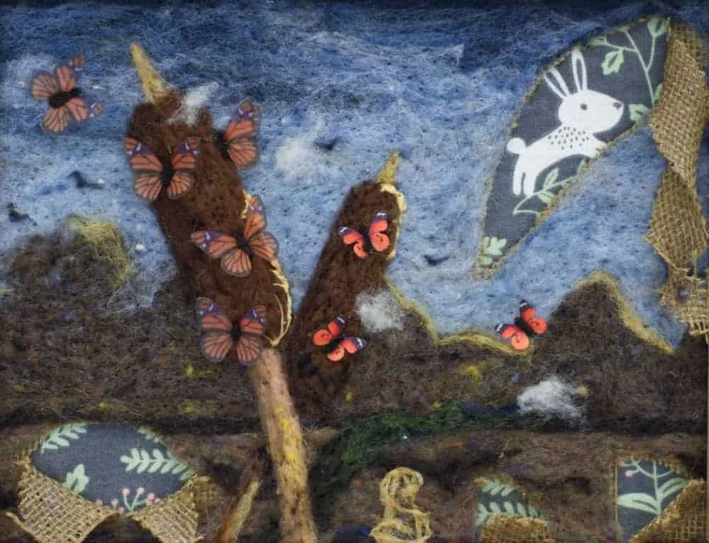 Two cattails bend over a marshy area of the koi pond. They are covered in monarch butterflies. Butterfles also fly around the area. Several cuts of peeled back burlap reveal a grey flannel printed with a leaping rabbit and other plant fronds