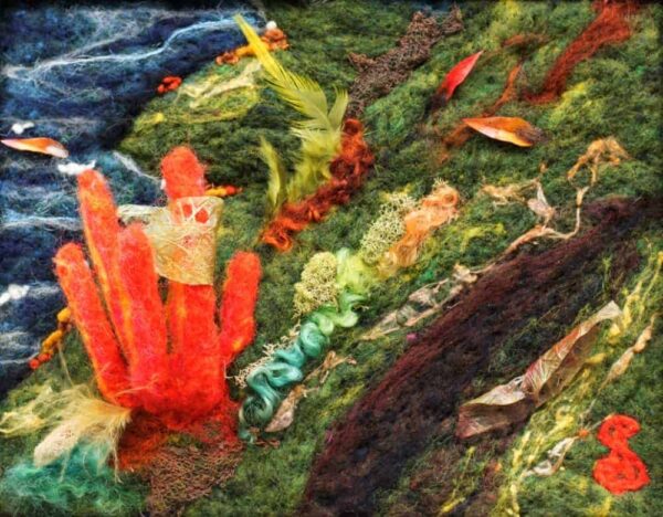 In the bottom left corner a red handshaped coral fungus protudes from the surface of the canvas. A leaf made of paper is wrapped around one of the fingers. In the upper left corner moving water is complimented by a leaf swirling in the water. The rest of the canvas is green and brown adorned with paper leaves and feather grasses. There is also reindeer moss by the base of the coral fungus